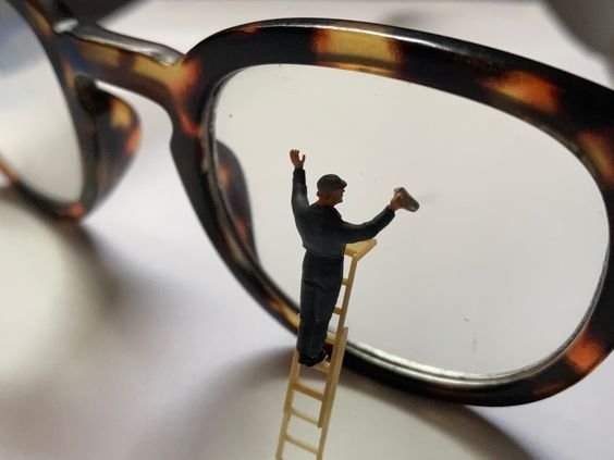 An old man standing on ladder and cleaning eyeglass lens