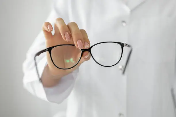Female optician hands giving new glasses to customer for testing Girl Holding Clear frame glasses